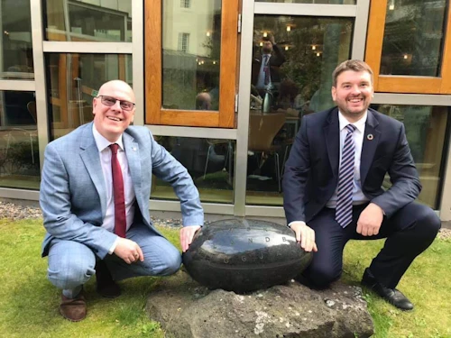Ásmundur Einar Daðason félags- og barnamálaráðherra og Kevin Stuart, húsnæðismálaráðherra Skotlands, við slípaðan íslenskan stein með áletruninni "með lögum skal land byggja" sem íslensk stjórnvöld færðu þeim skosku að gjöf þegar húsnæði skoska þingsins var vígt í Holyrood í Edinborg árið 2004.